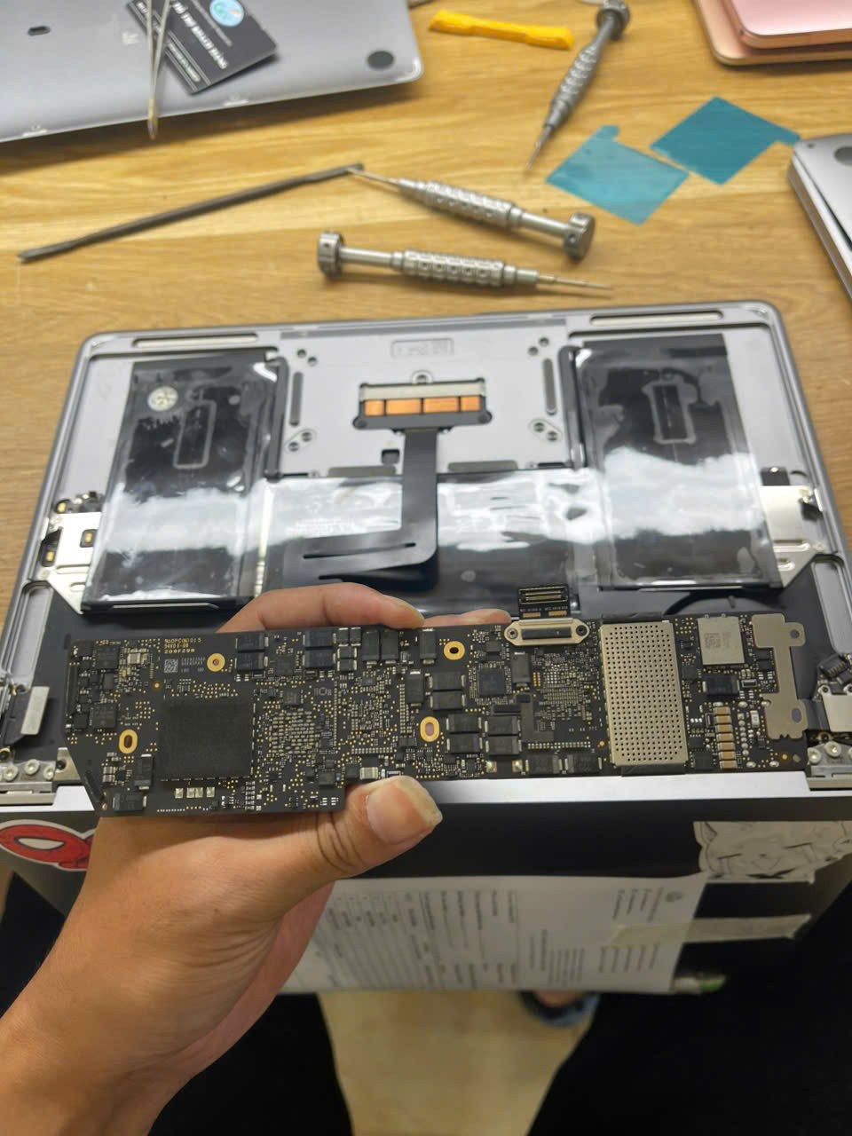 Bo mạch MacBook tháo rời bên cạnh thân máy trên bàn sửa chữa